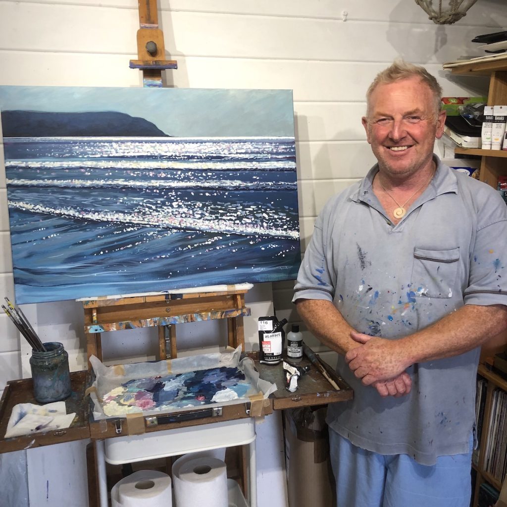 artist Steve PP stood next to his studio easel with the painting "Late Summer Sparkle" on it