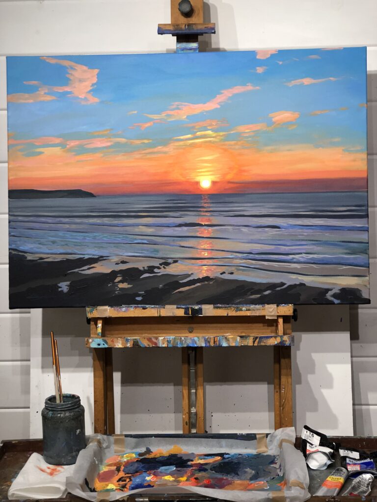 Painting of a Woolacombe sunset resting on an artist’s wooden easel in an art studio